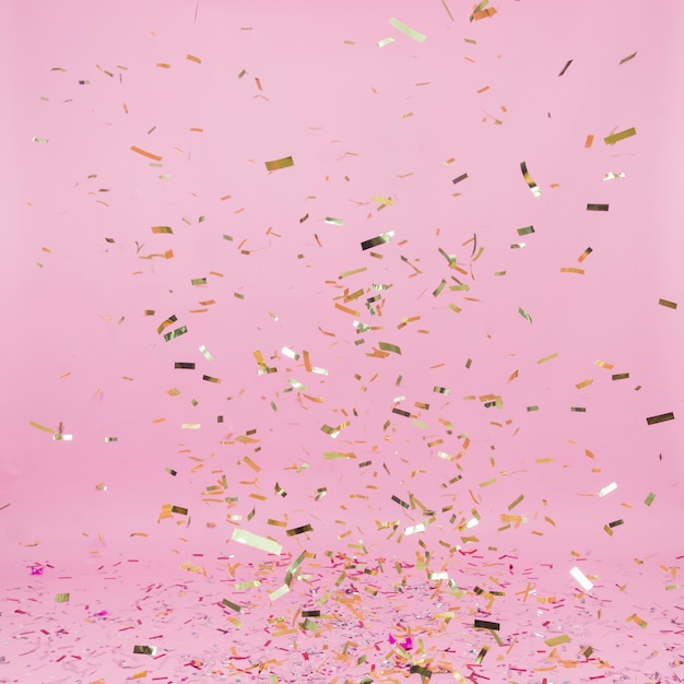 Dalende gouden confetti op roze achtergrond | Gratis Foto