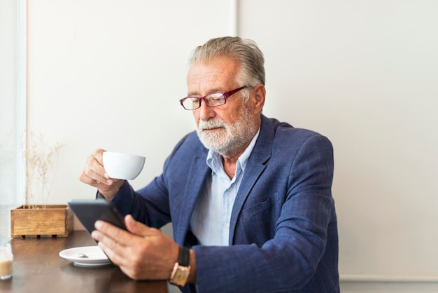 De bejaarde gebruikt digitale tablet Premium Foto