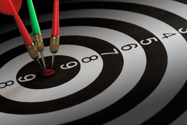 De close-up schoot rode en groene pijltjepijlen op centrum van dartboard, het concept van het doelsucces. Premium Foto