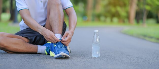 De jonge bindende loopschoenen van de atletenmens in het park openlucht Premium Foto