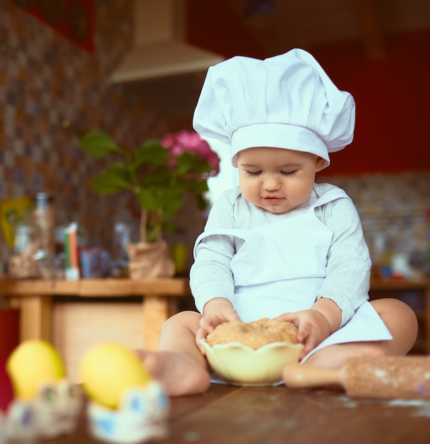 De kleine baby zittend op de tafel en spelen met deeg Gratis Foto