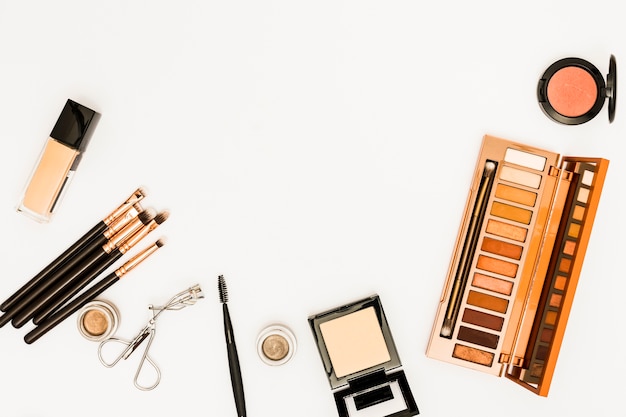 De make-uppalet van schoonheidsmiddelen met borstels en wimperskrulspeld op witte achtergrond wordt geïsoleerd die Gratis Foto
