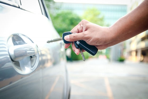 De mannelijke hand houdt de sleutel vast om de deur te openen om de auto te openen. Premium Foto