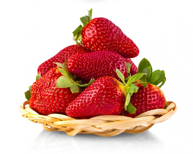 De rieten bruine mand met aardbeien die op witte achtergrond worden geïsoleerd. rijpe aardbeien close-up. Premium Foto