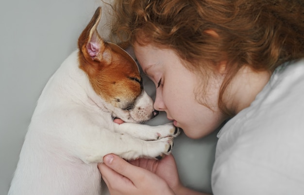 De zoete krullende meisje en puppyjasje russell hond slaapt in nacht. Premium Foto