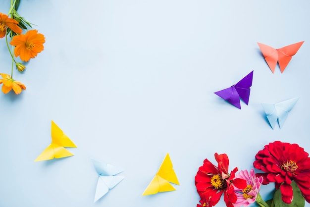 Decoratie met calendula goudsbloembloemen en origamidocument vlinders op blauwe achtergrond Gratis Foto
