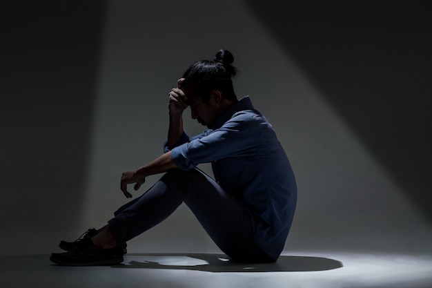 Een aziatische man lijdt aan depressies in de duisternis. Premium Foto