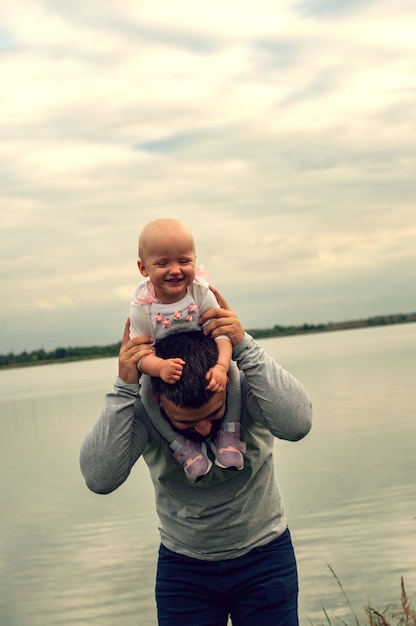 Een Kind In De Nek Van Zijn Vader Loop Langs Het Water Baby En Papa Tegen De Hemel Premium Foto