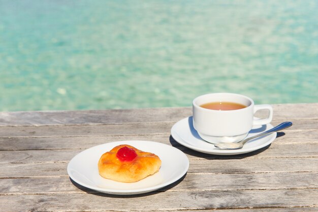 Een kopje thee op tafel met de zee op de achtergrond Premium Foto