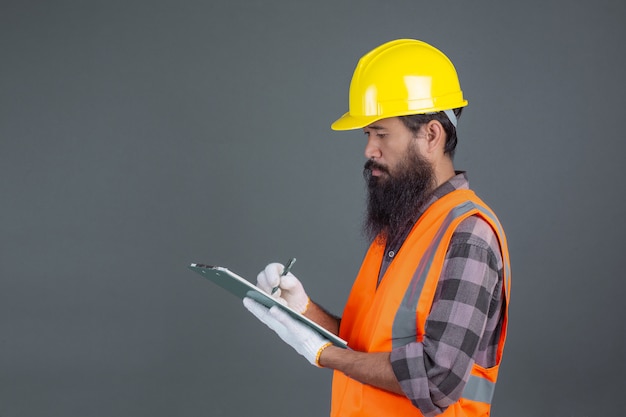 Een technische man met een gele helm met een ontwerp op een grijs. Gratis Foto