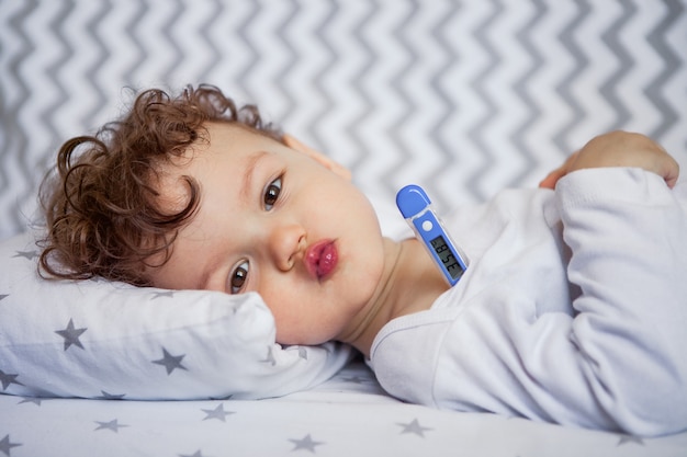 Emotionele baby ligt in de wieg. lichaamstemperatuur. thermometer onder de arm. gezond slapen bij een temperatuur. in slaap vallen. Premium Foto
