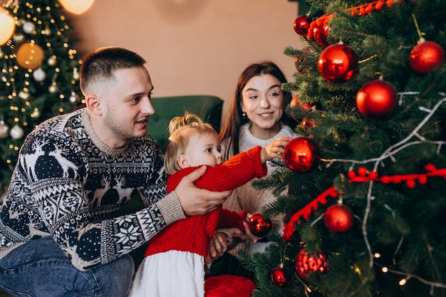 Familie met weinig dochter hangend speelgoed op kerstboom Gratis Foto