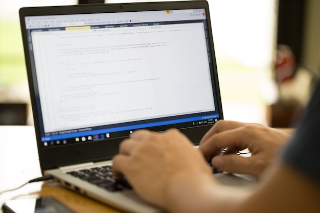 Freelance programmeur of ontwikkelaar die thuis werkt en broncode intypt met laptop Premium Foto