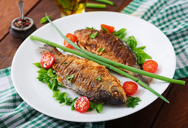 Gebakken vis karper en verse groente salade op houten tafel. Gratis Foto