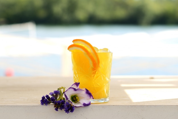 Gele cocktail met sinaasappel, limoen en ijs in een glazen tuimelaar Premium Foto