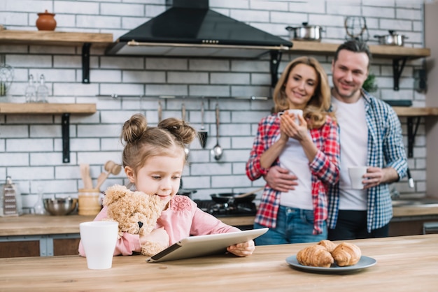 Gelukkige moeder en dochter die hun jong geitje bekijken die digitale tablet in keuken gebruiken Gratis Foto