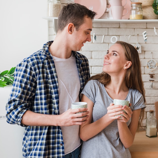 Gelukkige paar verliefd samen in de keuken op zoek naar elkaar Gratis