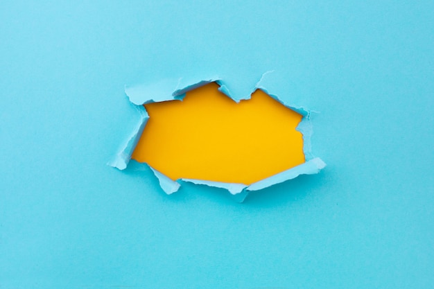 Gescheurde gat in blauwe kleur en geript van papier met gele achtergrond. gescheurde document textuur met exemplaar ruimtegebied voor tekst Gratis Foto