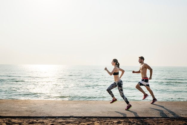Gezond jong paar die door het strand samen lopen Premium Foto