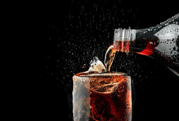 Giet frisdrank in glas met ijs splash op donkere achtergrond. Premium Foto