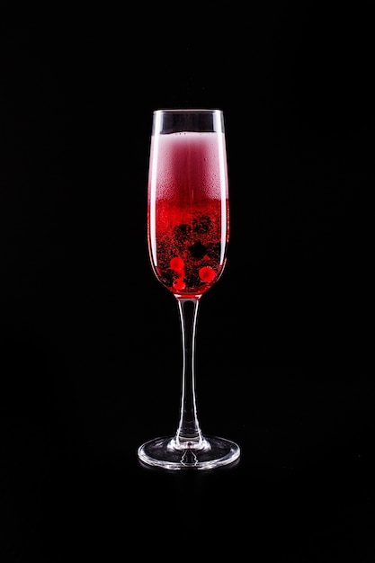 Glas met bessen en rode champagne alcohol cocktail staat op zwarte achtergrond | Gratis Foto