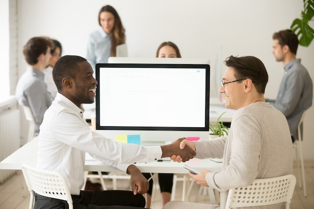 Glimlachen van diverse collega's handshaking vieren succesvol teamwerk, bedankt voor hulp Gratis Foto