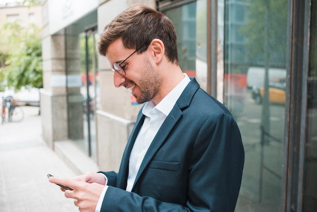 Glimlachende jonge zakenman die smartphone gebruikt Gratis Foto