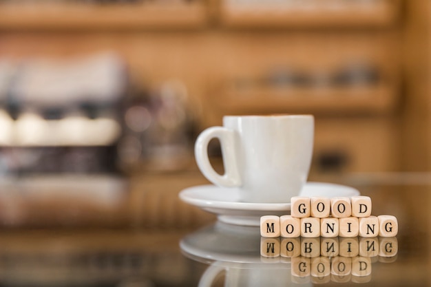 Goedemorgen houten blokken met kop van koffie op glasteller Gratis Foto