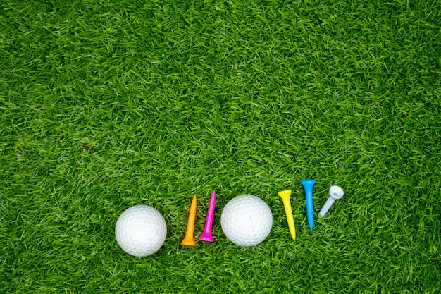 Golfballen en t-stukken zijn op groen gras. Premium Foto