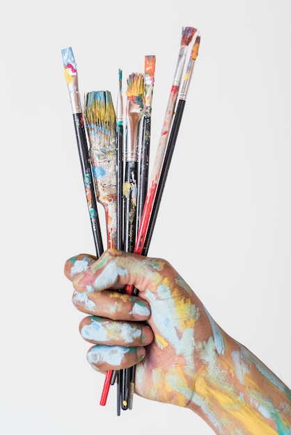 Hand met penselen gekleurd met verf Gratis Foto