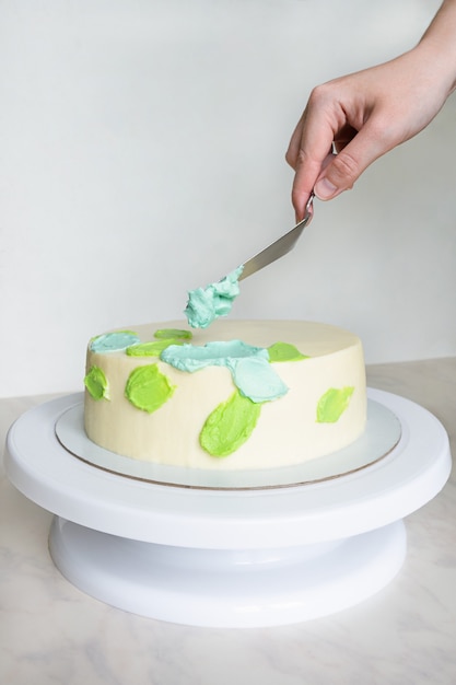 Handen met een versieren taart met groene en blauwe | Premium Foto