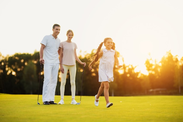 Happy family leisure golfers walk by fairway. Premium Foto