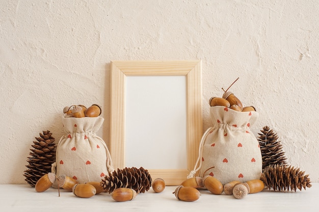 Herfst samenstelling met mock up frame, eikels in linnen tassen en dennenappels Premium Foto