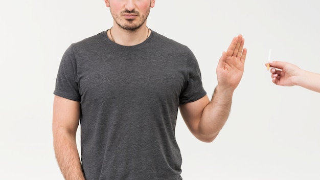 Het close-up van een mens weigert de sigaret die door een persoon wordt aangeboden die op witte achtergrond wordt geïsoleerd Gratis Foto