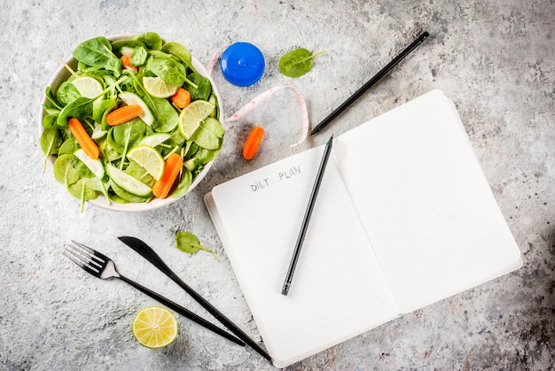 Het gewicht van het dieetplan verliest de salade van de concepten verse groente met van de de notepadgrey steen van het vorkmes de lijst Premium Foto