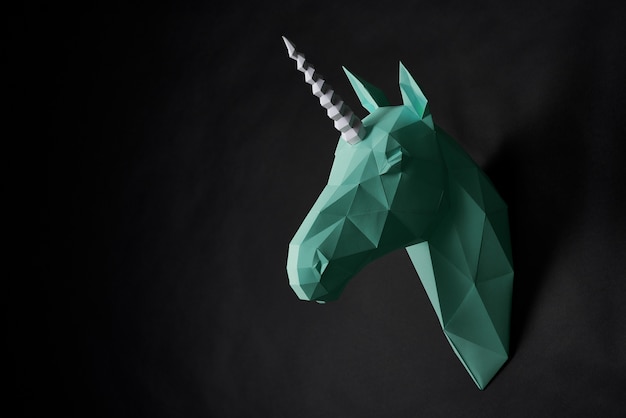Het hoofd van de origami het groene eenhoorn hangen zwarte muur. | Premium Foto