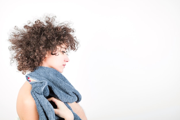 Het zijaanzicht van jonge vrouw met krullend haar veegt haar lichaam met handdoek af tegen witte achtergrond Gratis Foto