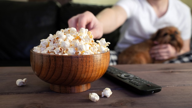 Houten schaal met gezouten popcorn en tv-afstandsbediening. Premium Foto