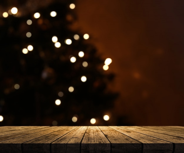 Houten tafel kijkt uit naar een defocussed kerstboom Gratis Foto