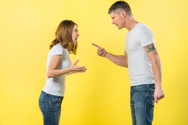 Jong paar dat zich face to face ruzie met elkaar bevindt tegen gele achtergrond Gratis Foto