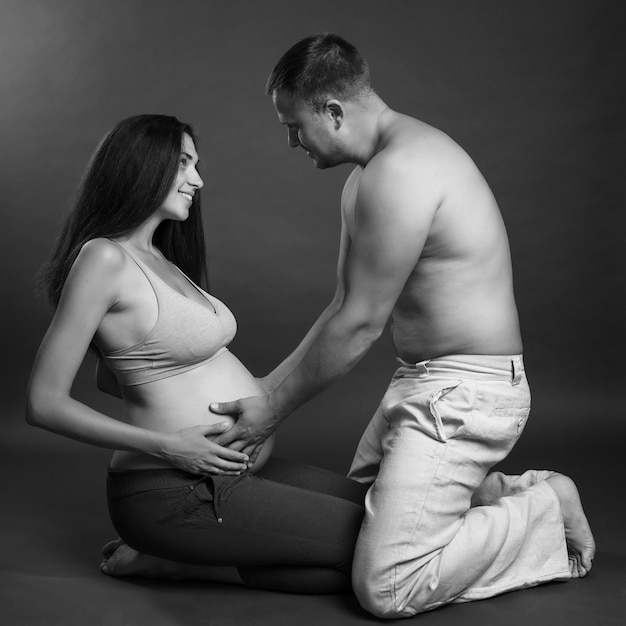 Jong zwanger en paar dat koestert glimlacht. liefde en tederheid. wachten op een wonder. zwart en wit portret Premium Foto