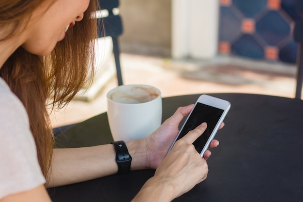 Jonge aziatische vrouw met smartphone mock up leeg zwart scherm in café Gratis Foto