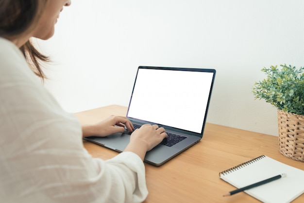 Jonge aziatische vrouw werken met behulp van en typen op laptop met mock up leeg wit scherm Gratis Foto