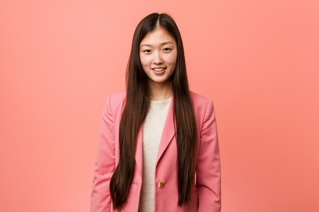 Jonge bedrijf chinese vrouw die roze gelukkig, glimlachend en vrolijk kostuum draagt. Premium Foto