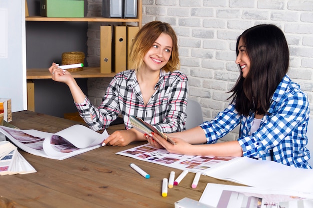 Jonge freelancers interieurontwerpers werken nieuw appartementproject in ontwerpstudio uit. de vrouwelijke vergadering van het twee vrouwenmeisje met ontmoet bureau met speld op schetstekeningen en ontwerpen van nieuw project Premium Foto