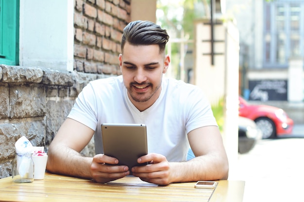 Jonge man in coffeeshop café met behulp van een tablet. Premium Foto