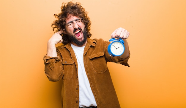 Jonge man met gek haar in beweging en een wekker Premium Foto