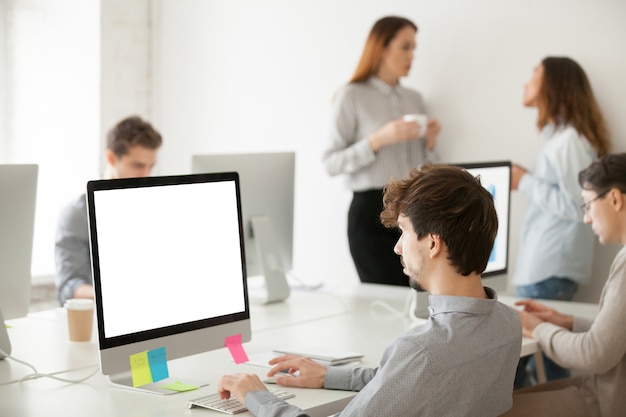 Jonge mannelijke werknemer die aan computer schrijven e-mail in bureau werkt Gratis Foto