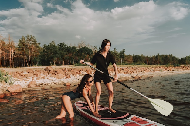 bezoeker Autonomie Bestuiven Jonge meisjes in wetsuit roeien surfen met peddel. | Premium Foto
