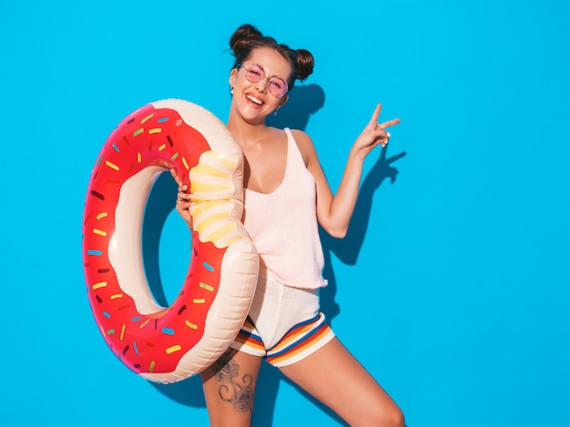 Jonge mooie sexy glimlachende hipster vrouw in zonnebril. met donut lilo opblaasbaar matras. Gratis Foto